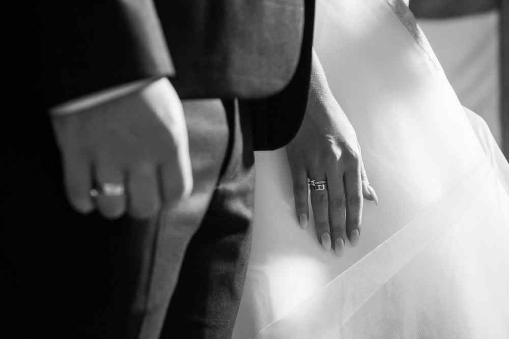 Bride and groom holding hands, wedding rings visible